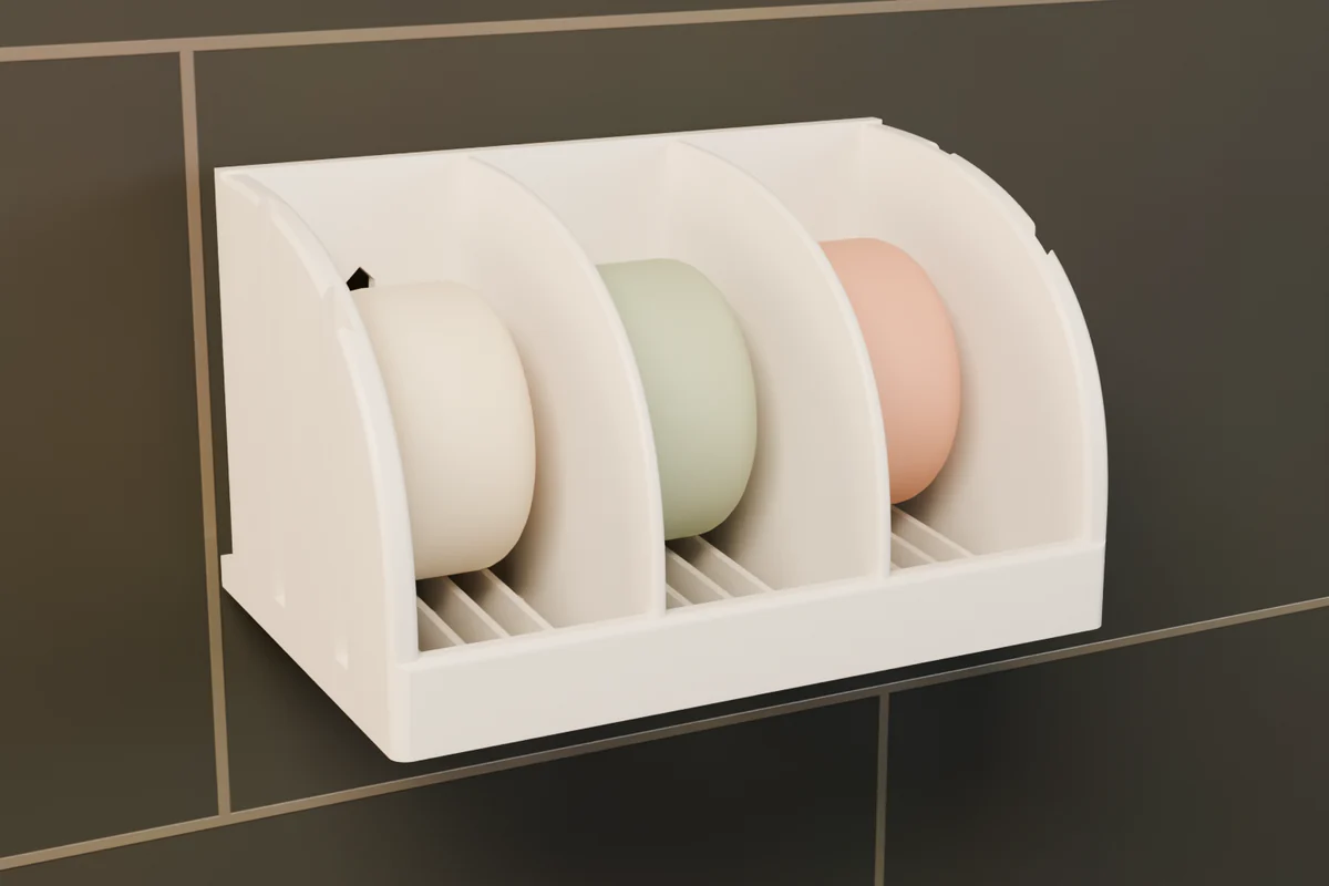 A white 3-Box Soap Holder on a dark tiled shower wall with three bars of soap.