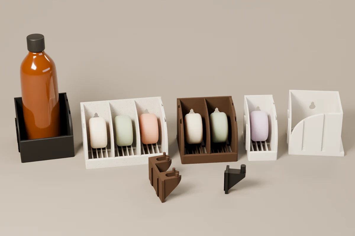 All seven MPrints pieces in mixed finishes: a black Bottle Holder, marble 3-Box, wood 2-Box, white 1-Box Add-On, white Corner Module, wood Razor Holder, and black Loofah Hook.